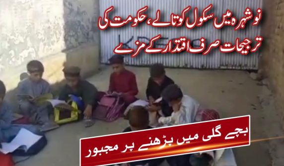 Children sitting outside a locked primary school gate in Khweshgi Bala, Nowshera, taking classes in open air due to school closure over land dispute.
